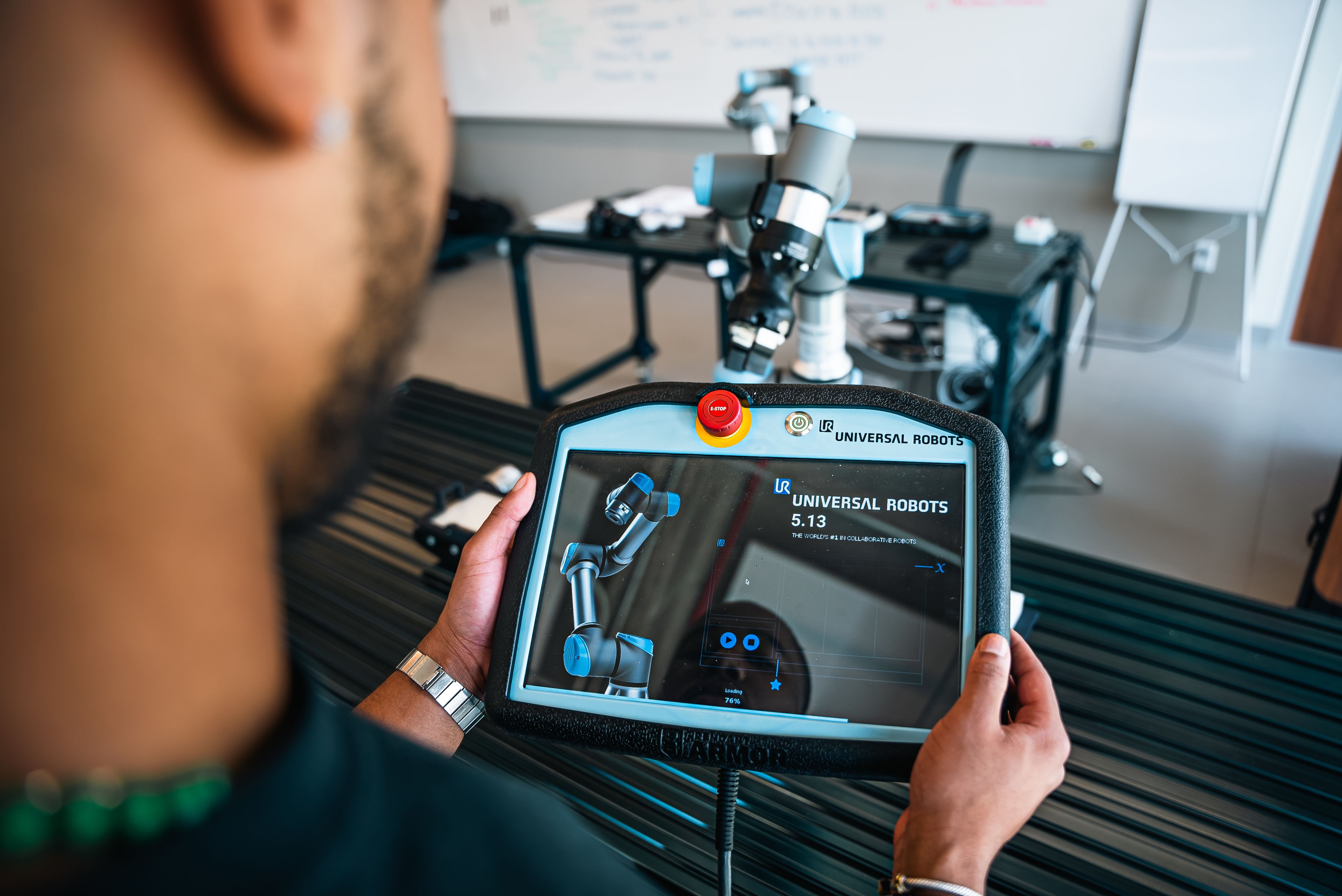 Over the shoulder shot of a male student programming a robotic arm in the lab