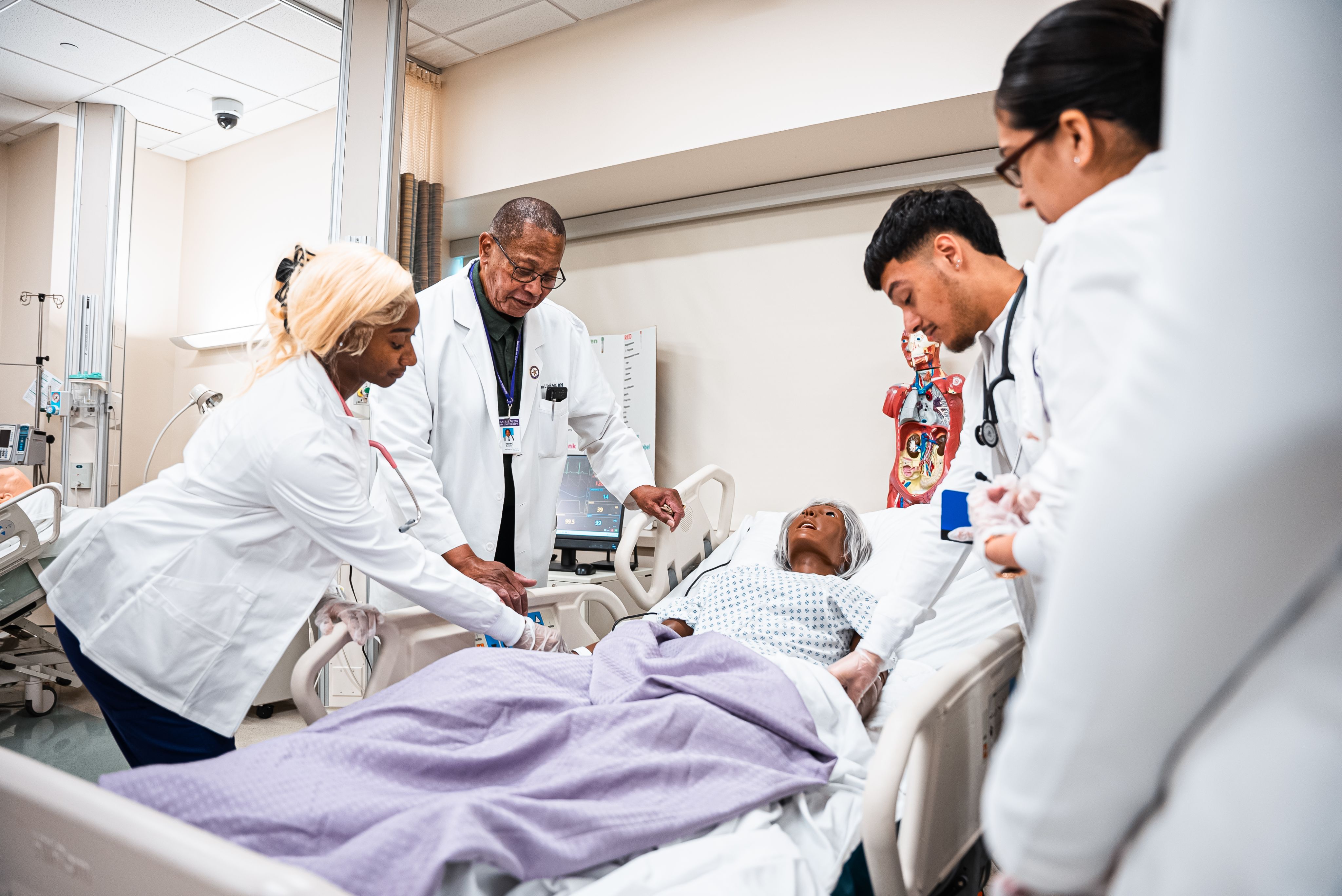 Female and male student checking vitals of medical dummy