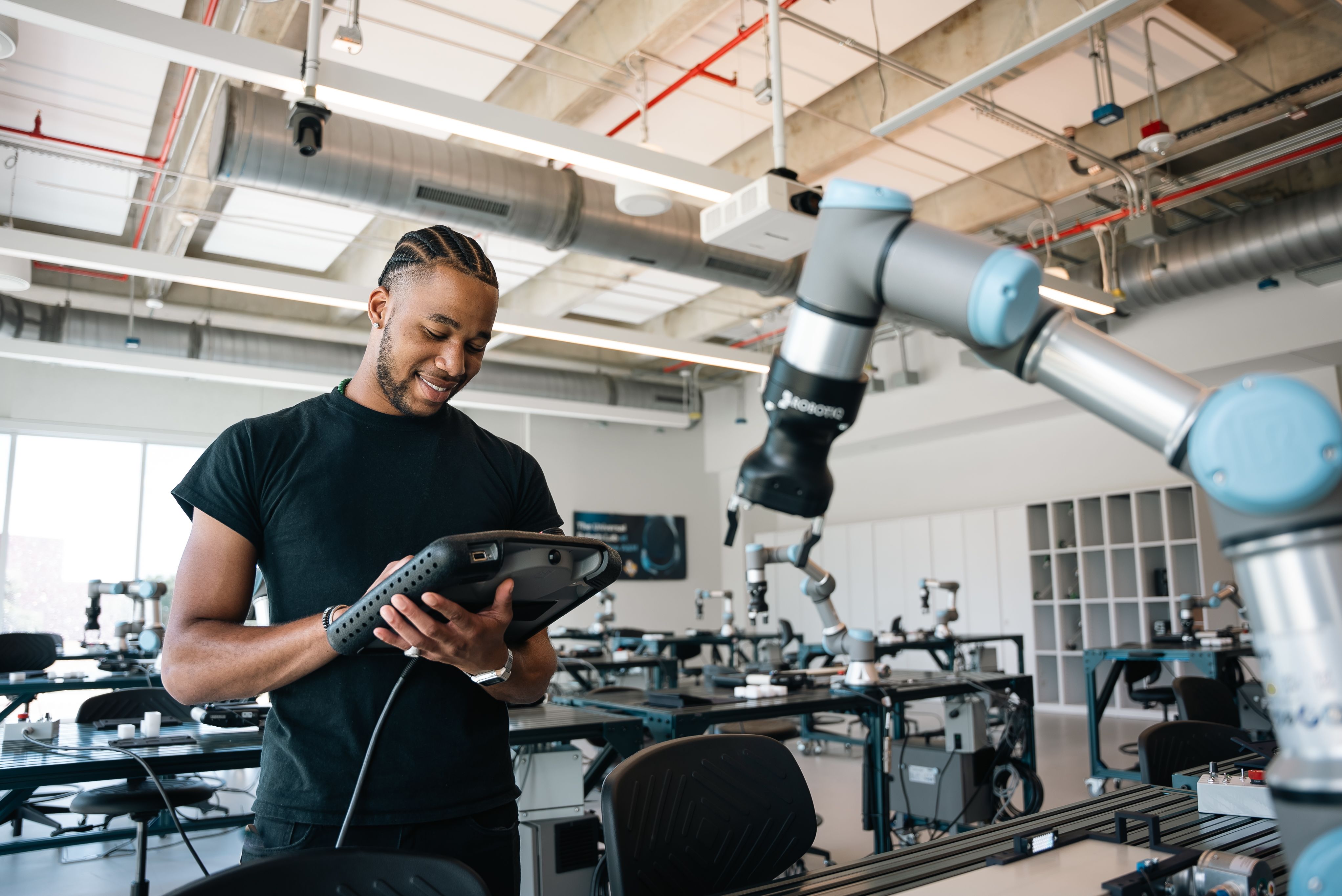 Male student programming a robotic arm in the lab