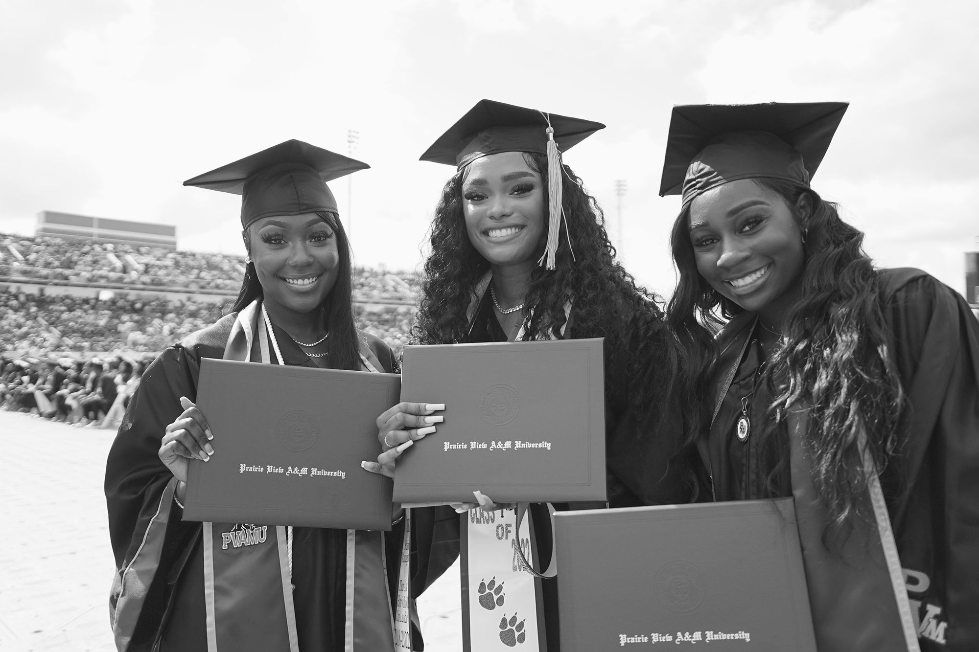 Three female graduates holding their degrees
